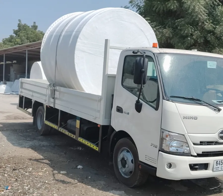 Large white GRP water tank strapped on a flatbed delivery truck in Dubai